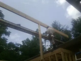 Carpenter setting a ridge beam over a new addition frame — Ice Dam Removal by Roofing Brothers in Kila