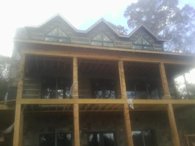Dormers and porch framing on a large log home under construction — Roof Coating work by our crew in Kila
