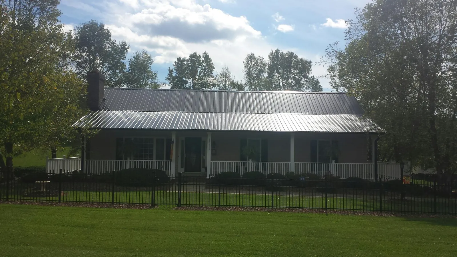 Gray metal roof on a brick ranch with a full width front porch — Gutter Guard Installation work by our crew in Kila