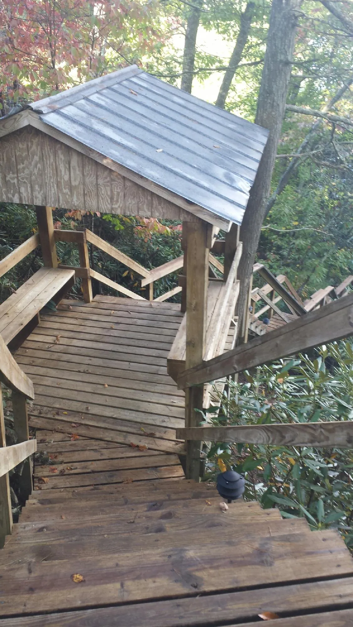 Metal roofed shelter over wooden steps on a wooded walkway — Skylight Repair & Installation work by our crew in Kila