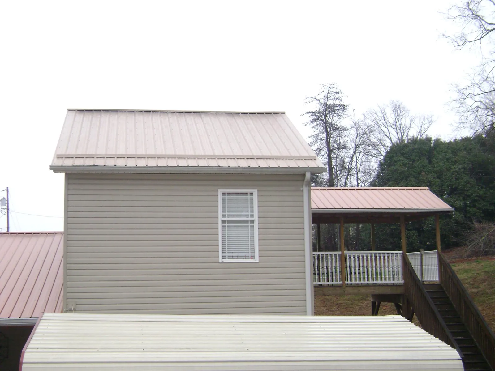 Tan metal roofs on a two story addition and attached porch, from a Roof Replacement job in Kila